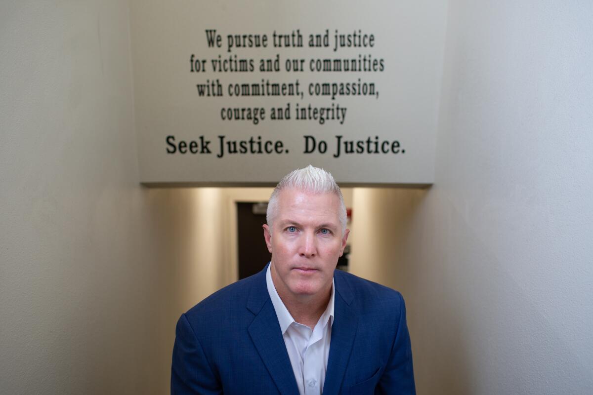 Jeff Reisig stands under words on a wall that include "Seek Justice. Do Justice."
