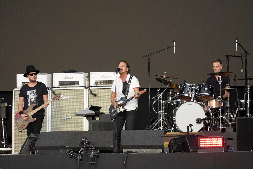 Eddie Vedder, centre, Matt Cameron, right, and Jeff Ament of Pearl Jam performing on a stage