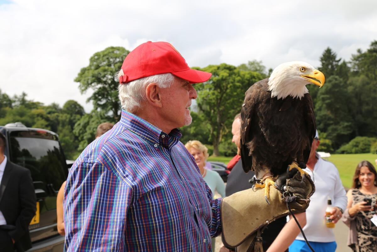 A man in a red hat holds a bald eagle.