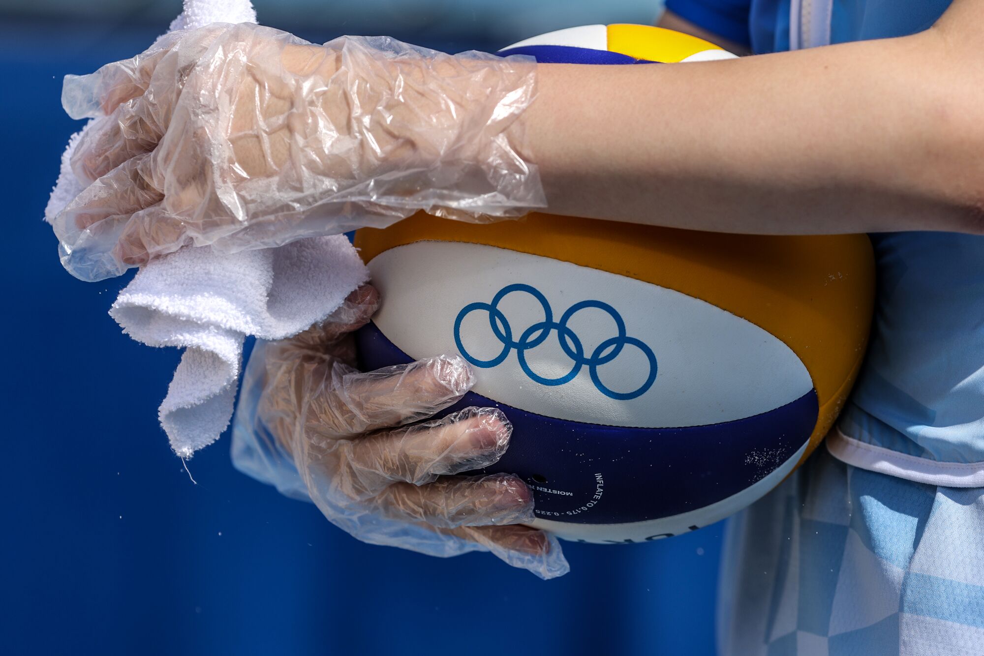 Volleyballs are wiped by assistants who wear plastic gloves to remain Covid-19 compliant