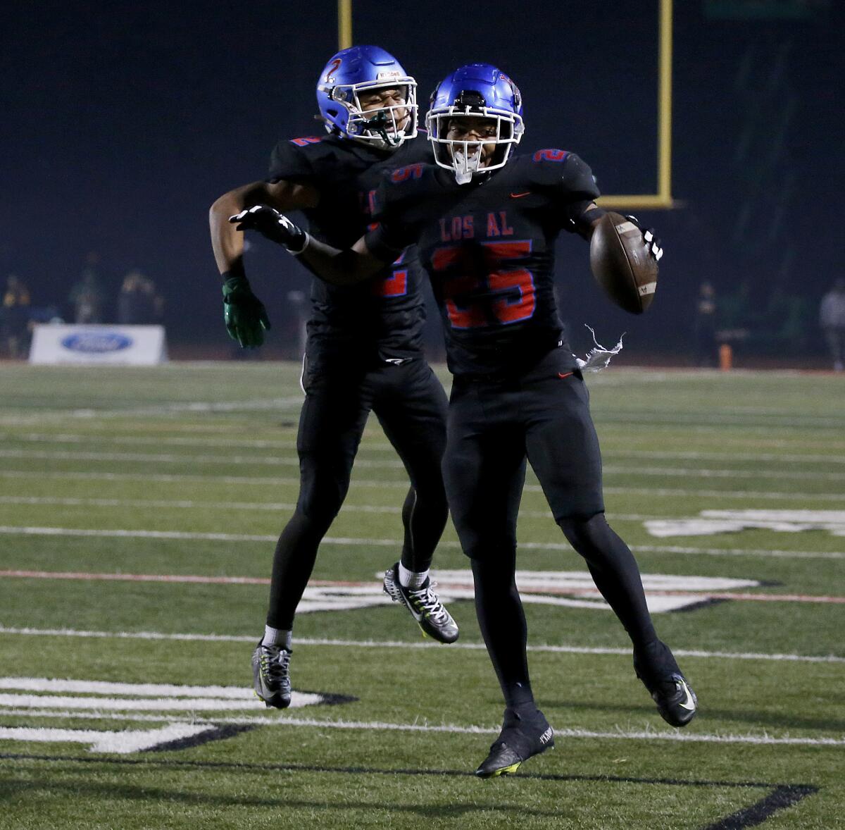 Los Alamitos running back Anthony League celebrates with teammate Gavin Porch by jumping in the air.