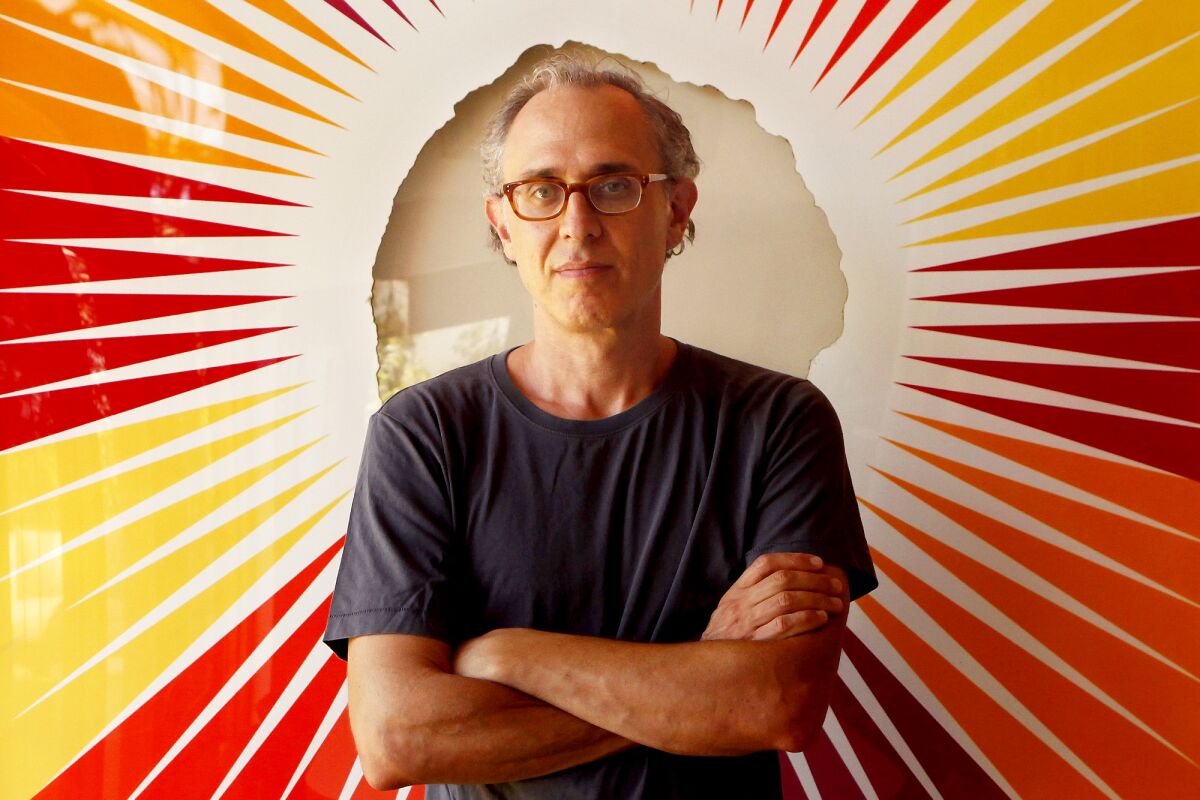 A portrait of Joshua Wolf Shenk, wearing glasses, a T-shirt and with his arms crossed