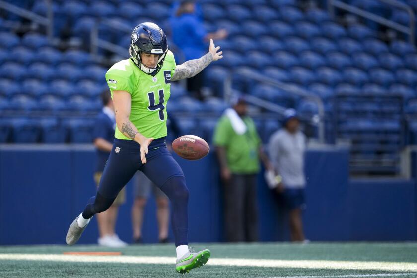 The Seahawks' Michael Dickson drops the ball, extends his arms and prepares to punt the football during warmups 