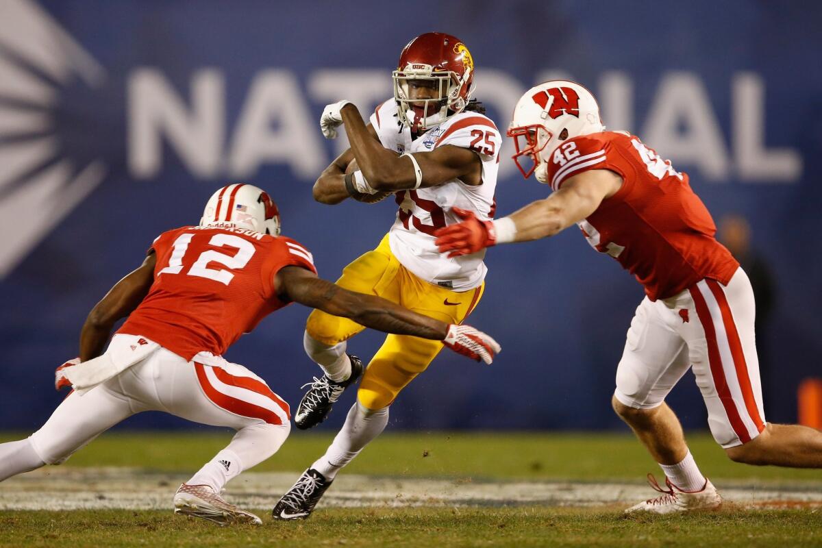 USC's Ronald Jones II runs through the defense of Wisconsin's Natrell Jamerson, left, and T.J. Watt during the Holiday Bowl in San Diego on Dec. 30, 2015.