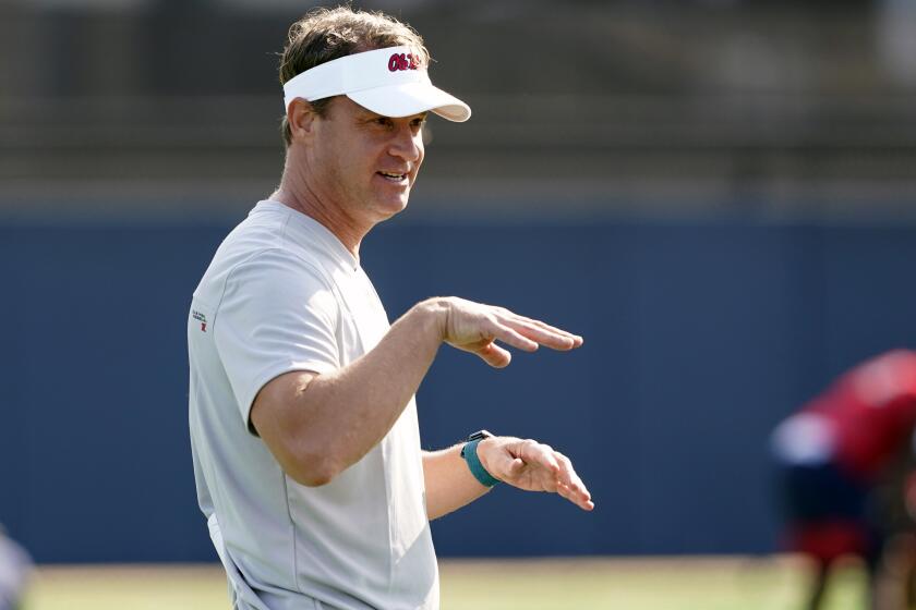 FILE - In this Aug. 9, 2021 file photo, Mississippi NCAA college football coach Lane Kiffin gestures towards his players during practice in Oxford, Miss. Kiffin will miss the opener against Louisville with a breakthrough case of COVID-19.Kiffin announced the positive test on Saturday, Sept. 4, two days ahead of the Rebels' opener in Atlanta.Kiffin, his staff and his players are all fully vaccinated. He said no other members of the team are expected to miss the game because of COVID-19.(AP Photo/Rogelio V. Solis, File)