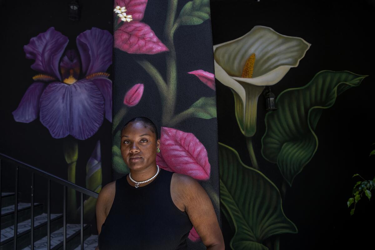 Zahria Eaves stands in front of large images of flowers.