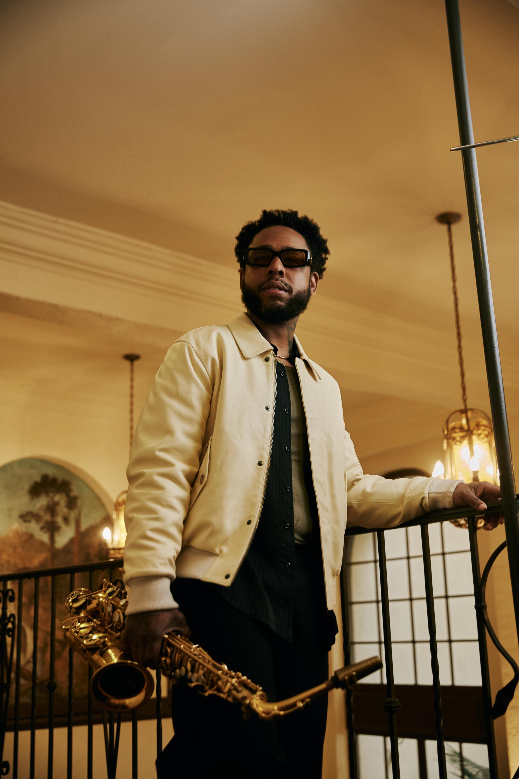 Terrace Martin stands holding a saxophone