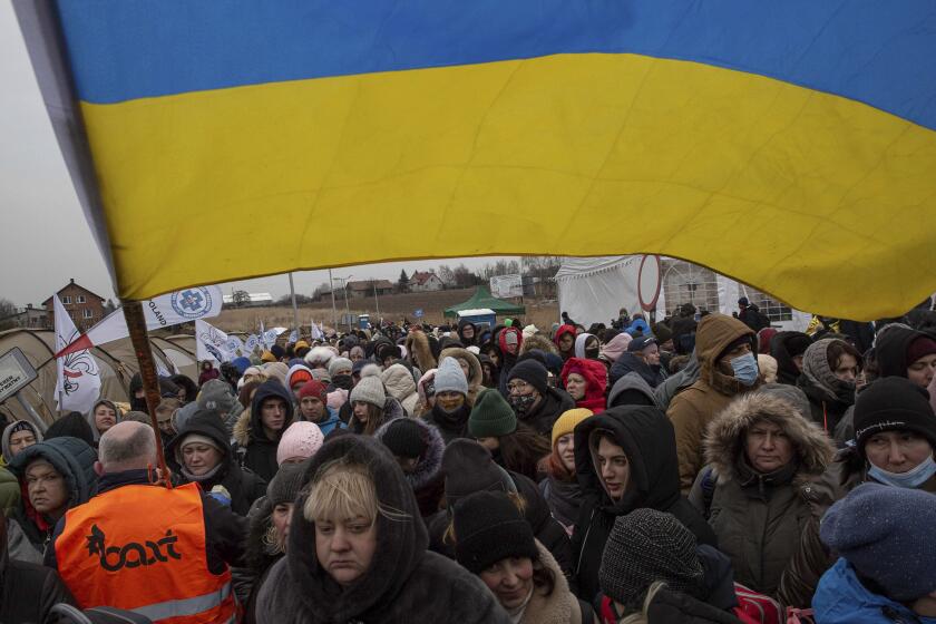 A Ukrainian volunteer Oleksandr Osetynskyi, 44 holds a Ukrainian flag and directs hundreds of refugees after fleeing from the Ukraine and arriving at the border crossing in Medyka, Poland, Monday, March 7, 2022. Russia announced yet another cease-fire and a handful of humanitarian corridors to allow civilians to flee Ukraine. Previous such measures have fallen apart and Moscow’s armed forces continued to pummel some Ukrainian cities with rockets Monday. (AP Photo/Visar Kryeziu)