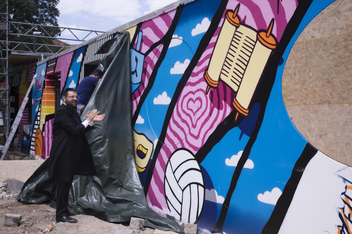 A rabbi unveiling a graffiti wall at the entrance of a new Jewish educational and cultural complex