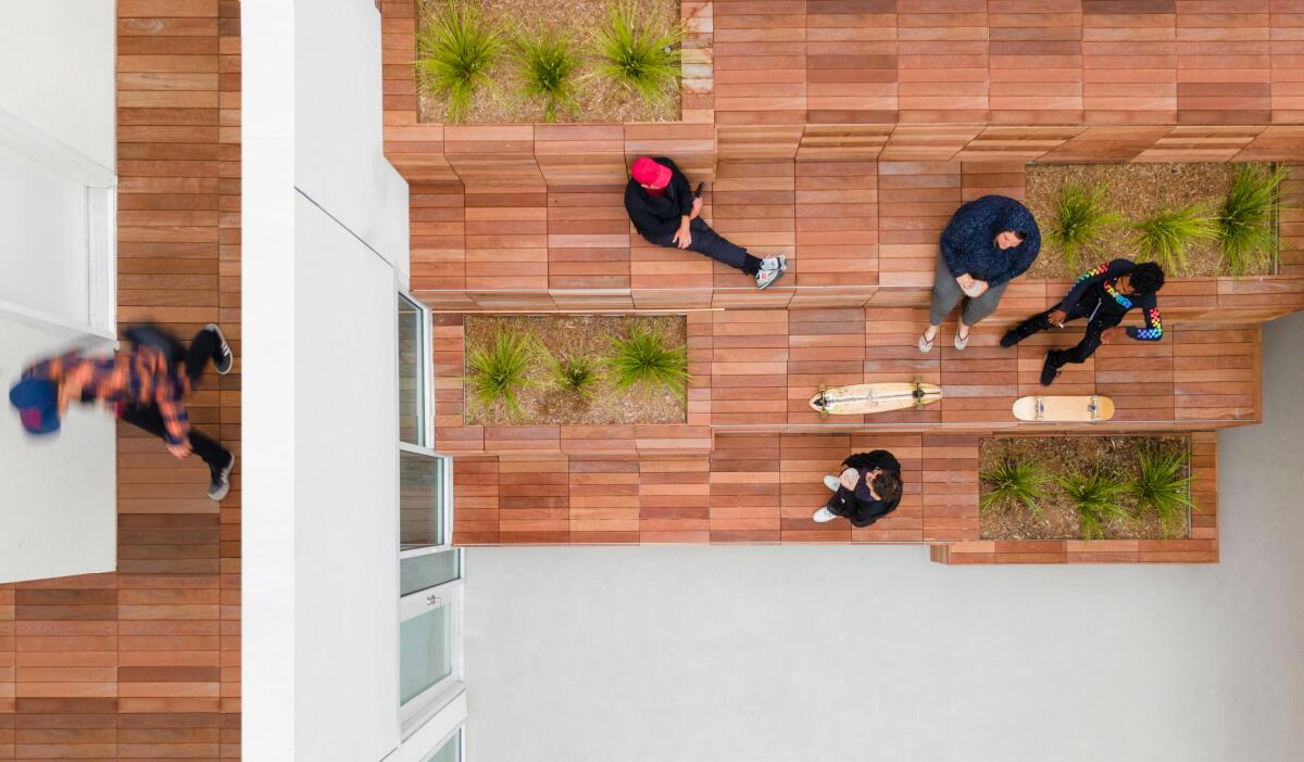An aerial view shows an apartment courtyard with stepped seating covered in wood with planters bearing succulents.