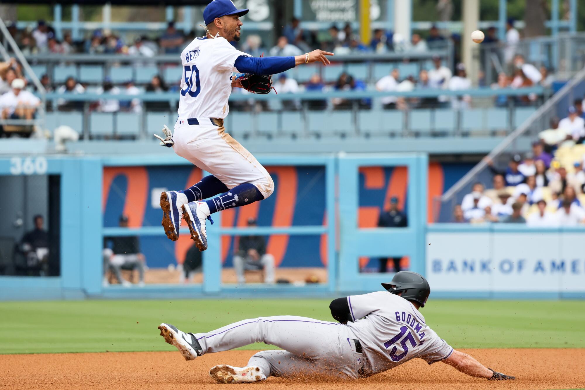 Dodgers shortstop Mookie Betts leaps over the Rockies' Hunter Goodman after throwing to first base in a game on June 2.