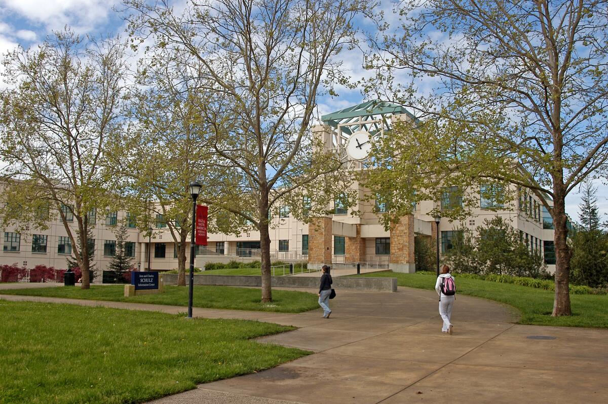 Two people walking on a tree-lined portion of Sonoma State's campus