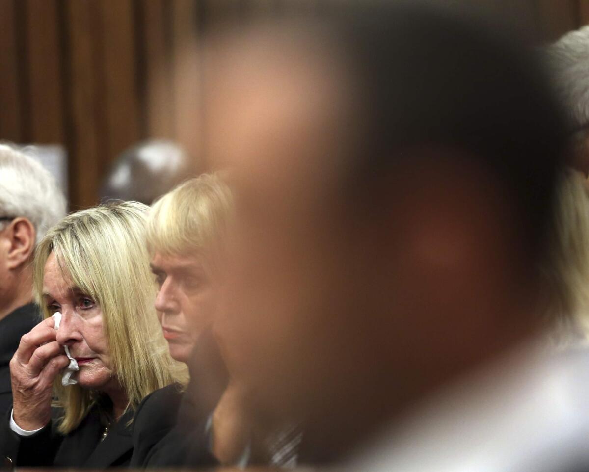 June Steenkamp wipes her face with a tissue at the start the trial of Oscar Pistorius, right, at the high court in Pretoria, South Africa, on Monday.