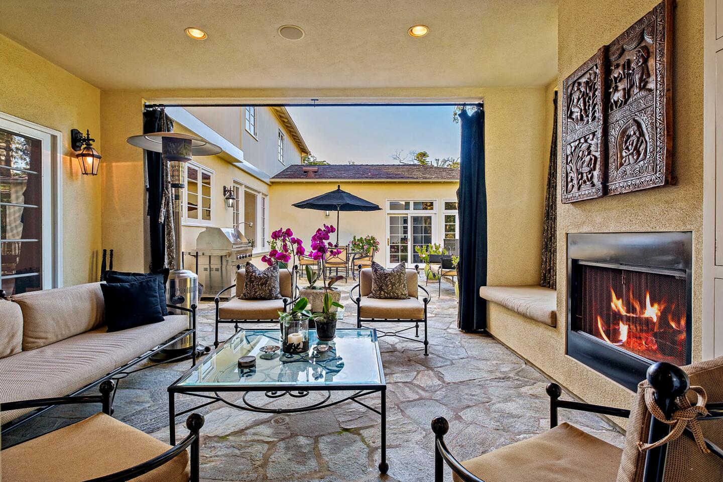 A spacious stone terrace has an outdoor dining area and covered lounge with a fireplace.