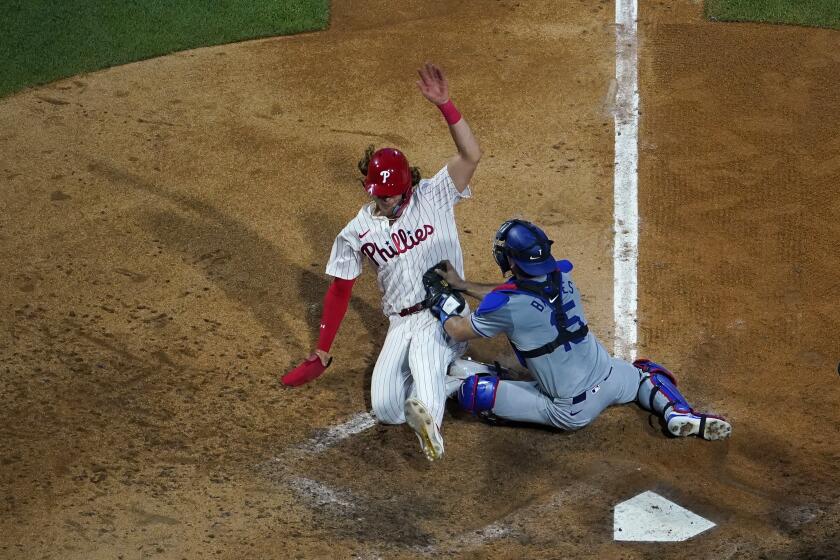 Philadelphia Phillies' Alec Bohm, left, is tagged out by Los Angeles Dodgers catcher Austin Barnes while trying to score during the fifth inning of a baseball game, Wednesday, July 10, 2024, in Philadelphia. (AP Photo/Matt Slocum)