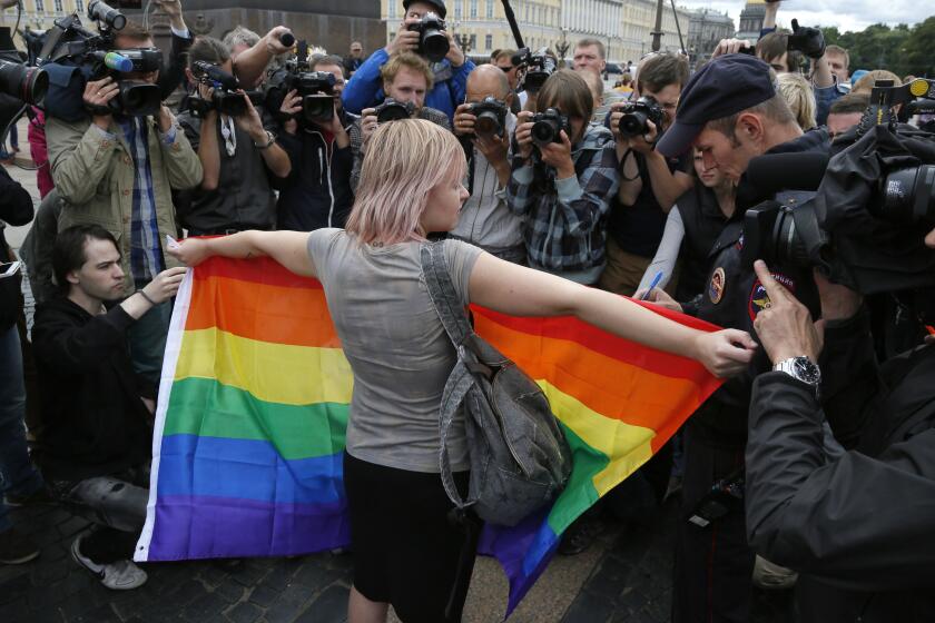 ARCHIVO - Defensora de los derechos de la comunidad LGBTQ+ muestra una bandera de arcoíris a los periodistas, durante una protesta en San Petersburgo, Rusia, el domingo 2 de agosto de 2015. (AP Foto, Archivo)
