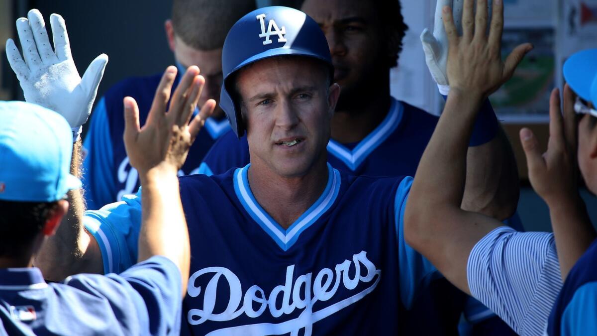 Dodgers second baseman Chase Utley is congratulated by teammates in the dugout after scoring a run against the Milwaukee Brewers.