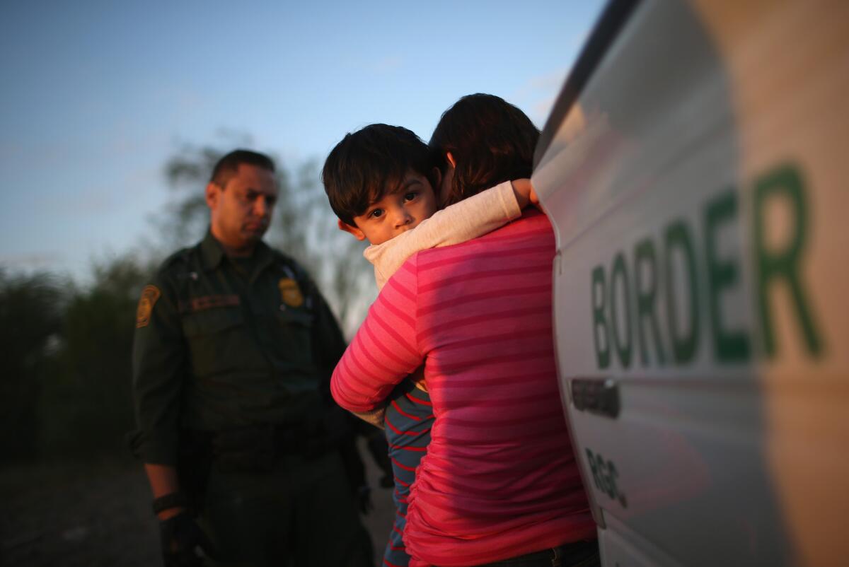 A 1-year-old from El Salvador clings to his mother after they surrendered to Border Patrol agents this week.