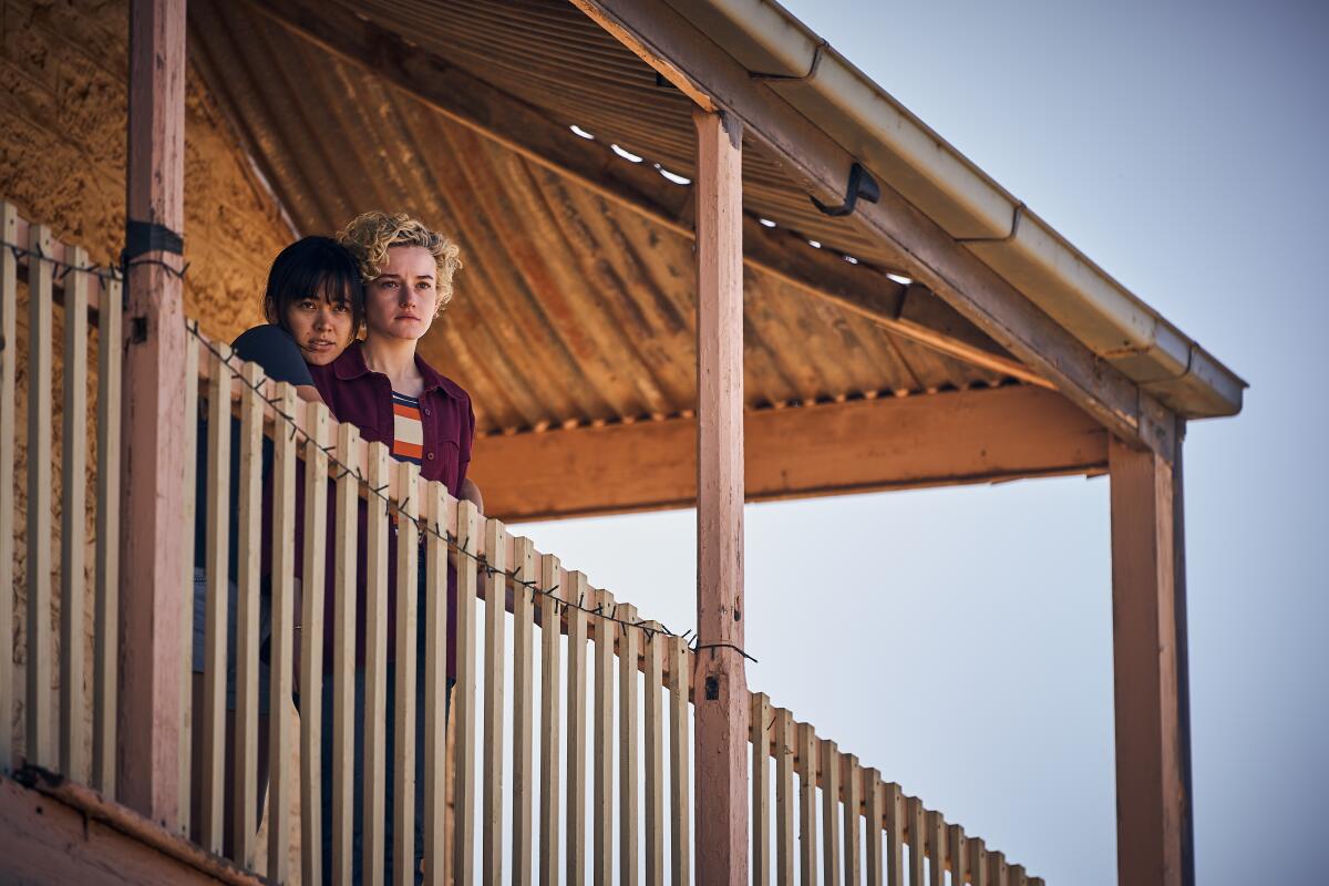 Two women stand on the balcony of a remote hotel.