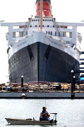 An angler in Long Beach Harbor fishes off the bow of the Queen Mary, which an organization called the Queen's Project wants to renovate and restore as a seaworthy luxury liner.