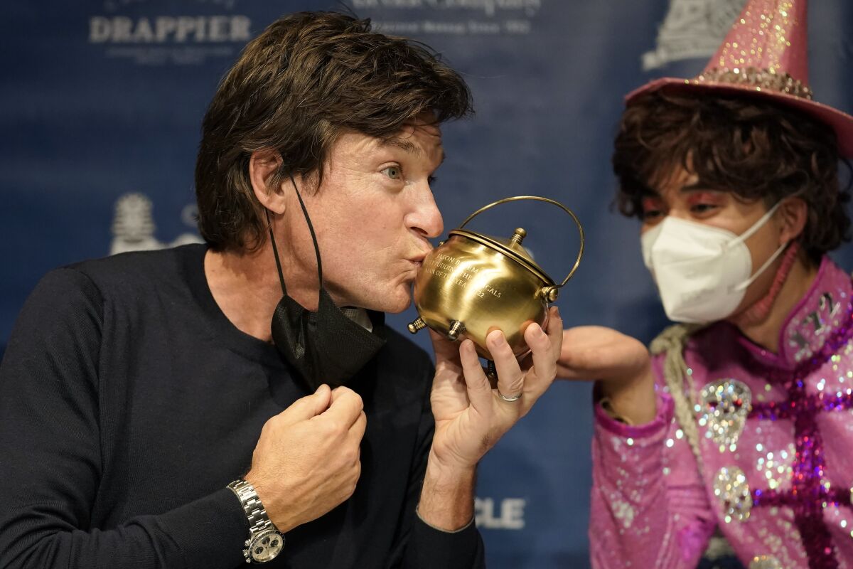 Harvard University's Hasty Pudding Theatricals 2022 Man of the Year, actor Jason Bateman, left, kisses the Pudding Pot during a news conference after being presented with the theatrical award, in Cambridge, Mass., Thursday, Feb. 3, 2022. (AP Photo/Steven Senne)
