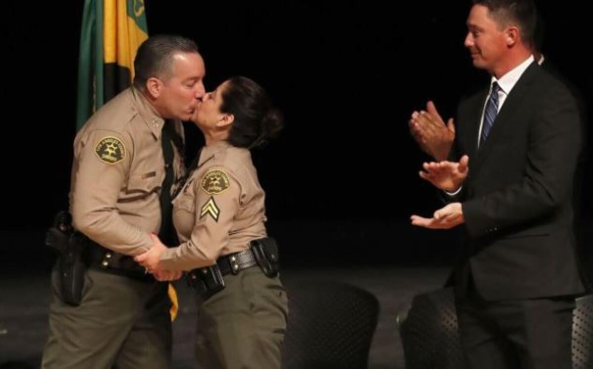 Alex Villanueva kisses his wife, Vivian, after he’s sworn in as L.A. County sheriff on Monday at East Los Angeles College in Monterey Park. The sheriff’s son, Jared, an Army veteran who served in Iraq, and granddaughter Christy applaud.