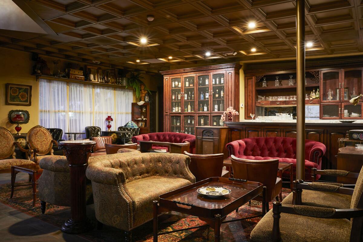 A room with wood paneling and shelves and upholstered chairs and couches. 
