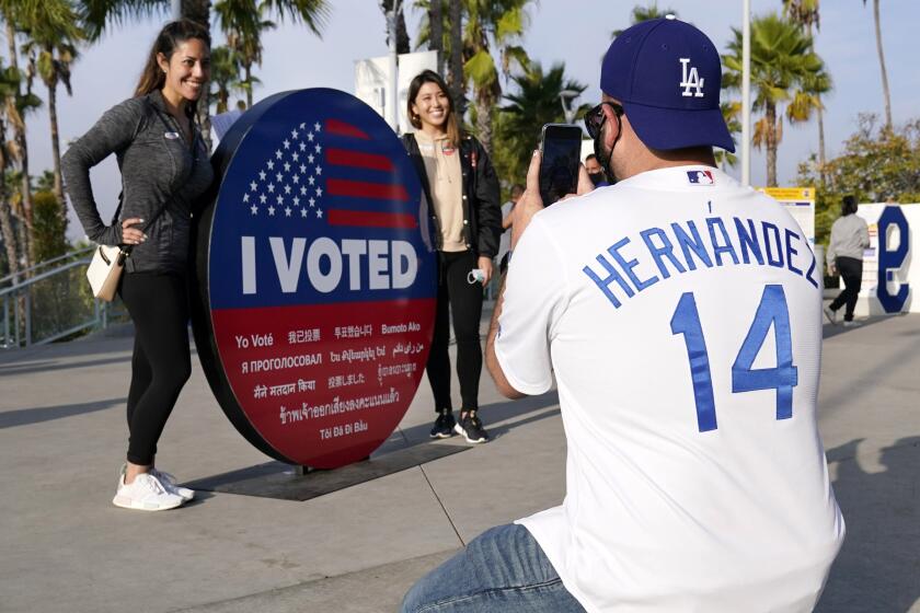 Shaun Butch, right, takes a picture of Matti Abramson, left, and Katherine Wong after they voted at Dodger Stadium.