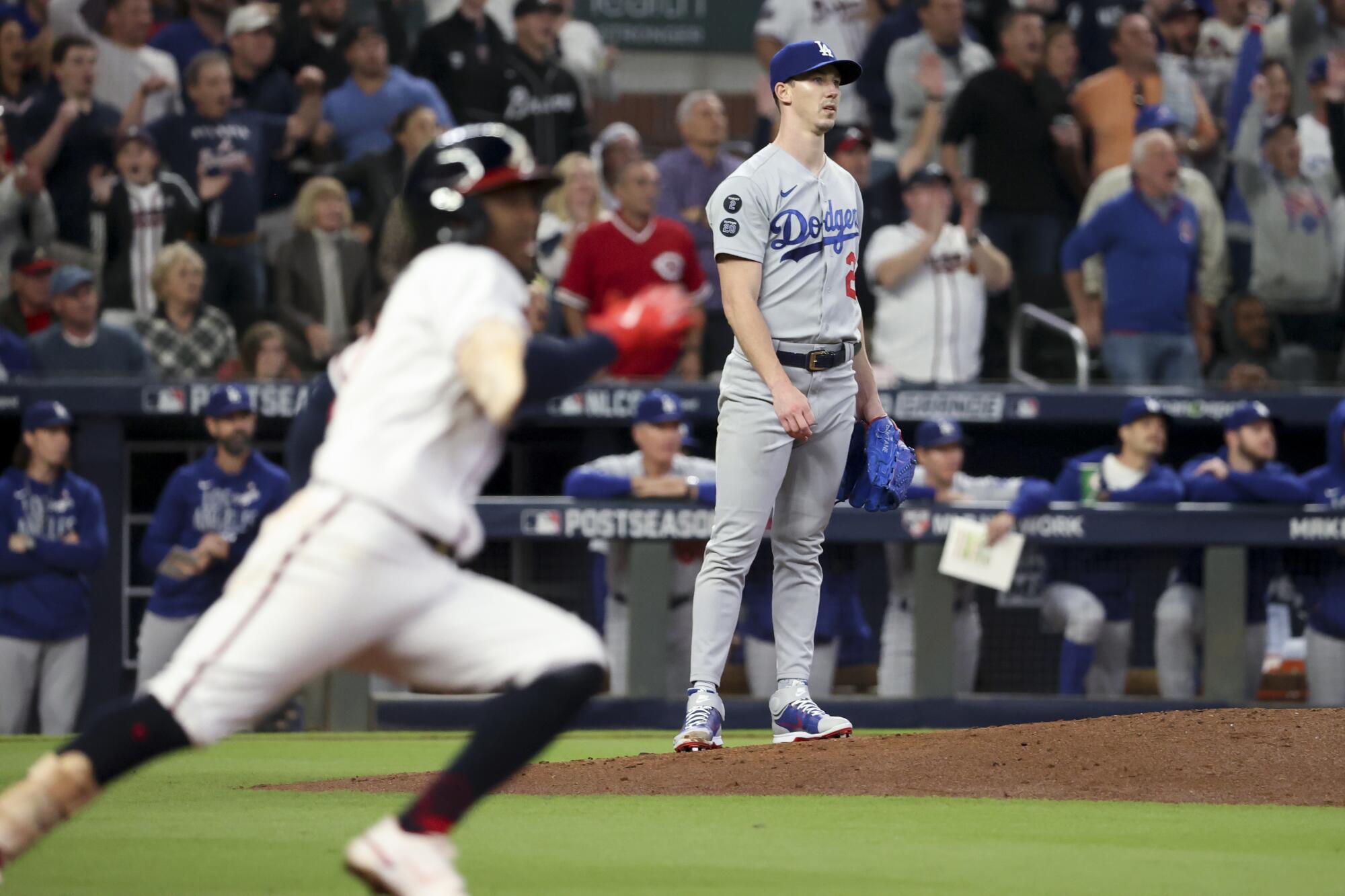 Dodgers starting pitcher Walker Buehler, right, looks up after a hit by Braves' Ozzie Albies.