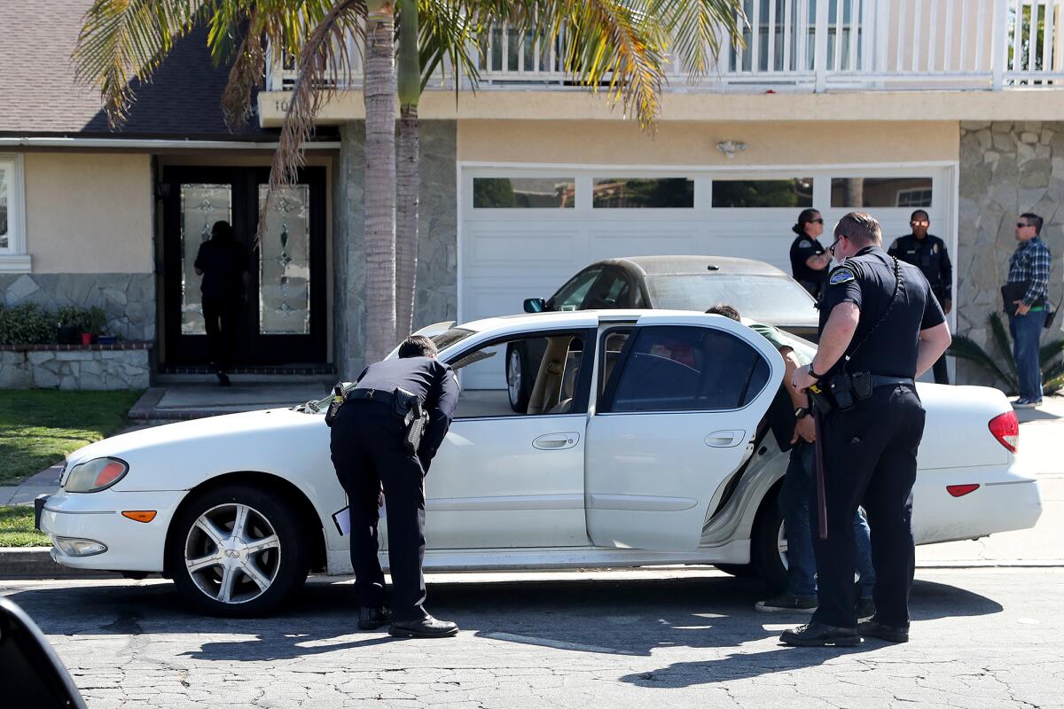 HBPD investigators search a white Infiniti sedan near a home on the 10000 block of Constitution Drive on Thursday.
