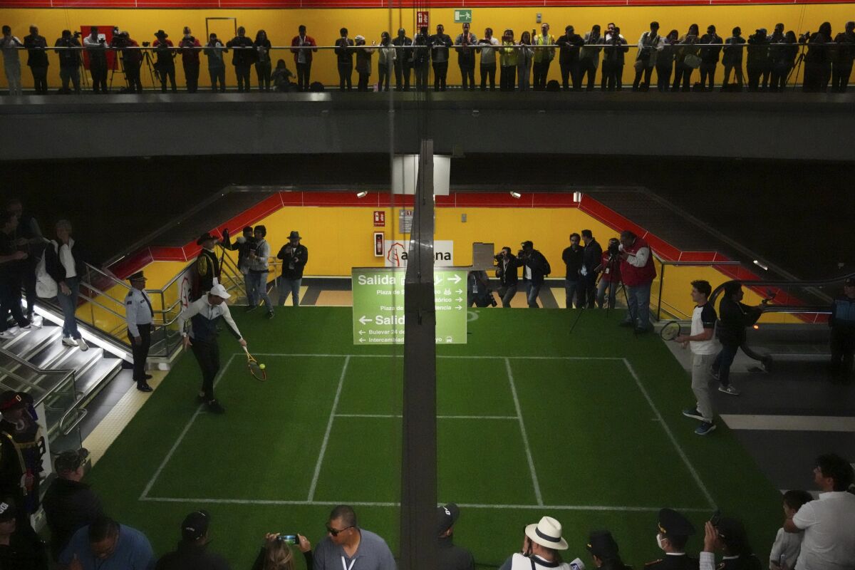 El tenista español Rafael Nadal, a la izquierda, devuelve una pelota al noruego Casper Rudd en una visita a una estación de metro de Quito durante su gira latinoamericana, en Ecuador, el domingo 27 de noviembre de 2022. (Foto AP/Dolores Ochoa)