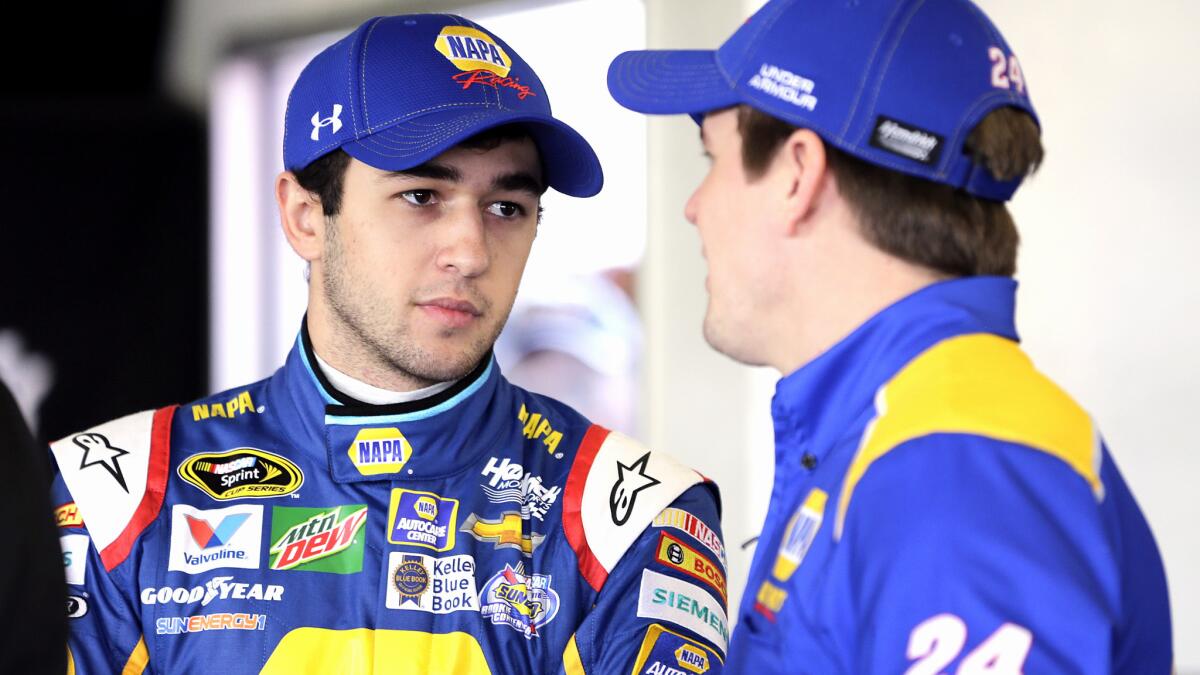 NASCAR driver Chase Elliott, left, talks with one of his crew members during a practice session for the Daytona 500.