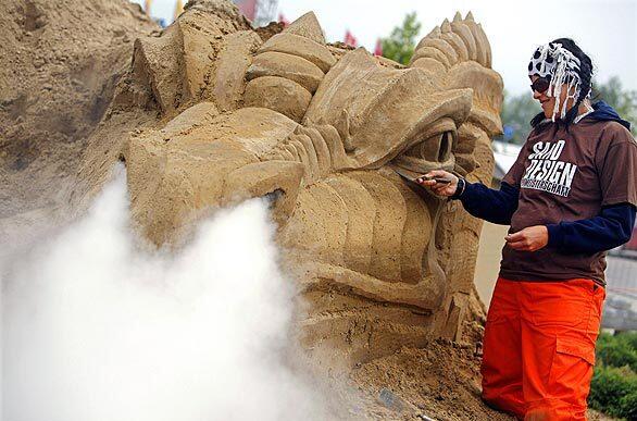Belgian sand designer Hanneke Supply works on a dragon that exhales steam in Guenthersdorf near Leipzig. Eight teams from 12 countries are competing in the second sand design world championship.