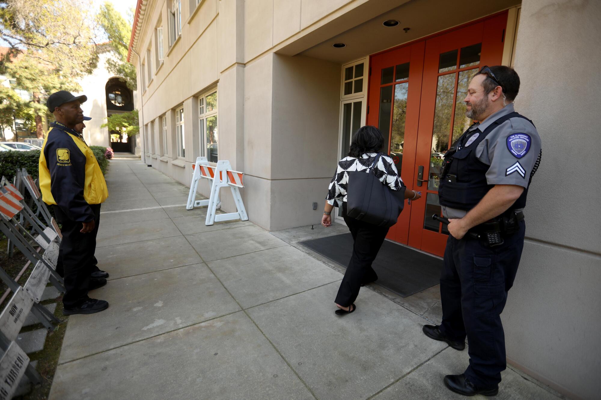 Campus safety officers stand outside a building while another person enters it.