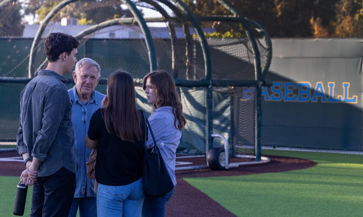 Cuatro personas conversan en un campo de béisbol.