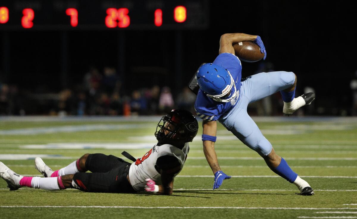 Norco running back Jaydn Ott tries to stay on his feet after getting hit by Corona Centennial defensive back Jaden Mickey.