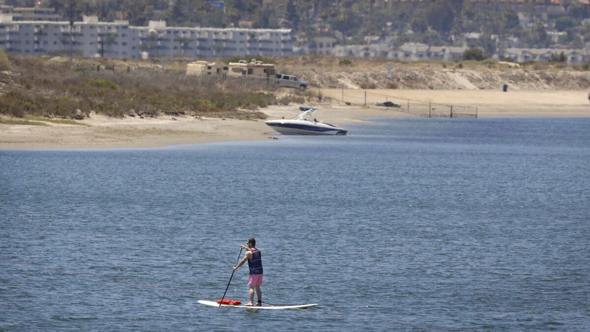 A paddleboarder makes his way through Mission Bay in June. A report on potential impacts of climate change warns that electrical substations in the Mission Bay and San Diego Bay areas could be vulnerable to rising sea levels in the coming decades.