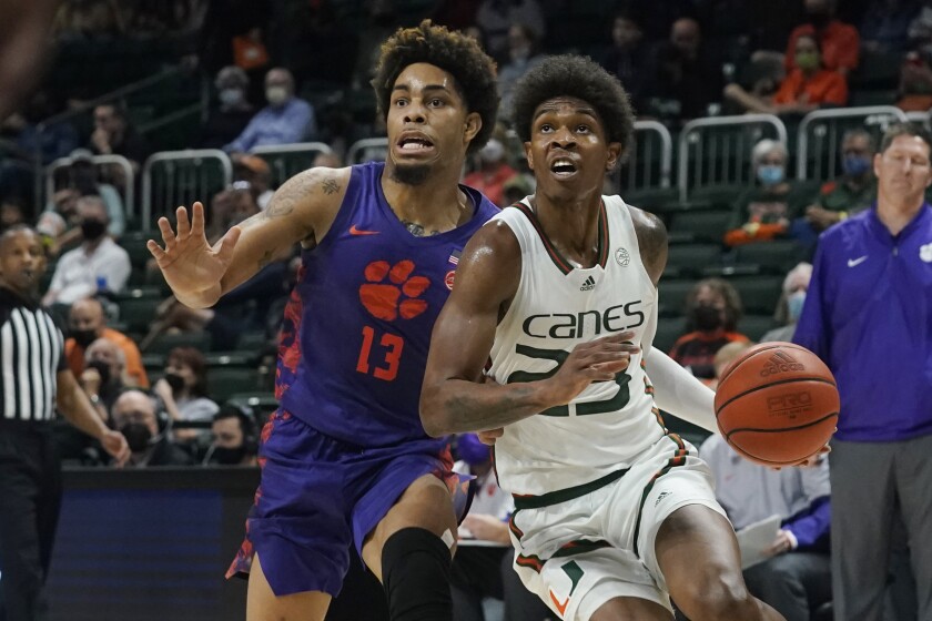 Miami guard Kameron McGusty (23) drives to the basket as Clemson guard David Collins (13) defends during the first half of an NCAA college basketball game, Saturday, Dec. 4, 2021, in Coral Gables, Fla. (AP Photo/Marta Lavandier)
