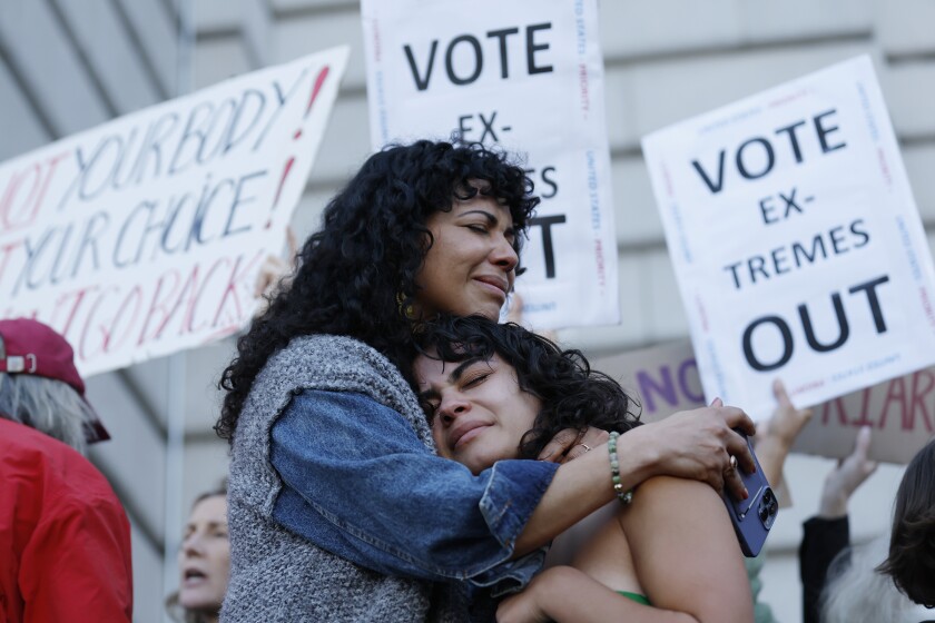 FILE - Mitzi Rivas, left, hugs her daughter Maya Iribarren during an abortion-rights protest at City Hall in San Francisco, following the Supreme Court's decision to overturn Roe v. Wade, Friday, June 24, 2022. The Supreme Court's ruling allowing states to regulate abortion has set off a mad travel scramble across the country to direct patients to states that still allow the procedure. (AP Photo/Josie Lepe, File)