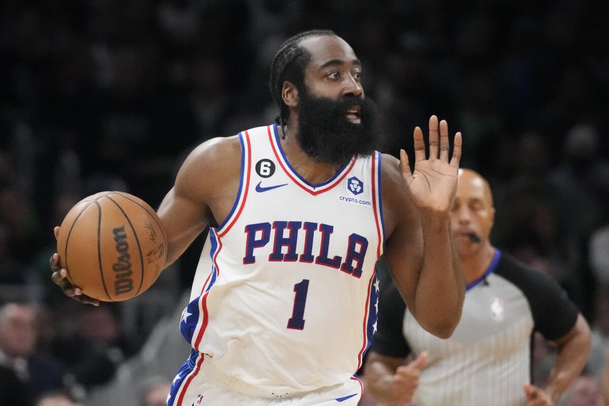 76ers guard James Harden holds his left hand up while calling to teammates during a game against the Celtics.
