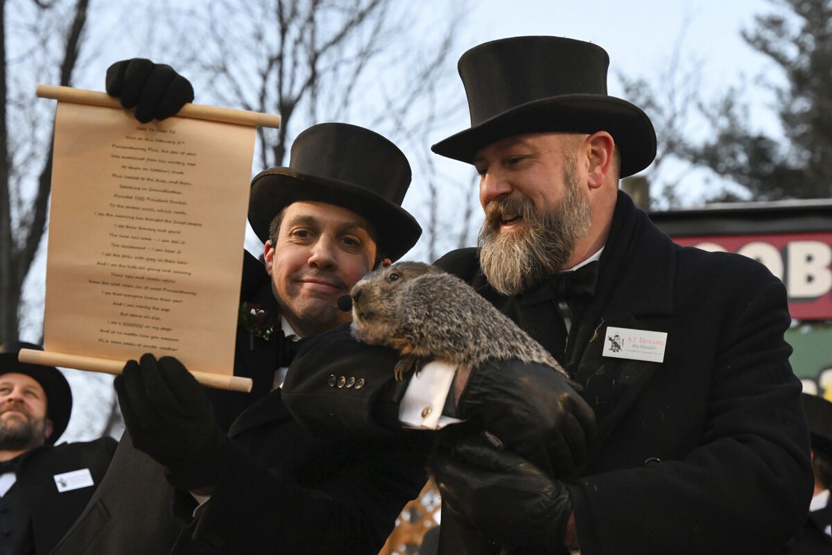 Groundhog Club handler A.J. Dereume holds Punxsutawney Phil, the weather prognosticating groundhog, while Vice President Dan McGinley reads the scroll during the 137th celebration of Groundhog Day on Gobbler's Knob in Punxsutawney, Pa., Thursday, Feb. 2, 2023. Phil's handlers said that the groundhog has forecast six more weeks of winter. (AP Photo/Barry Reeger)