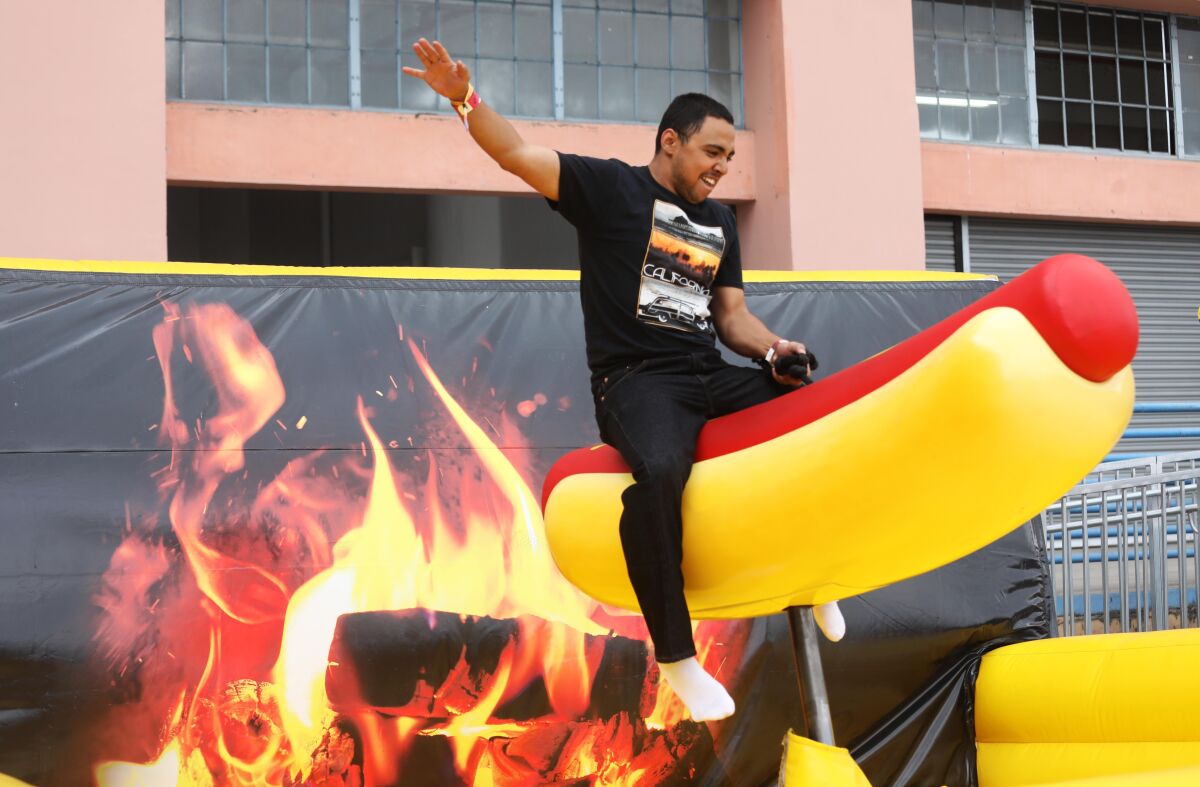 An adventurous attendee rides a giant mechanical hot dog at 2018 Adult Swim Fest