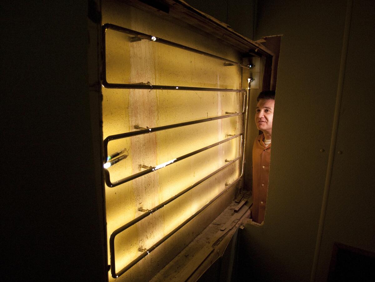 Andrew Meieran, the new owner of Clifton's Cafeteria, examines a neon light that was glowing behind a wall for about 60 years.