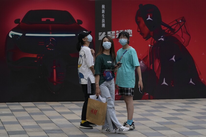 Shoppers past near advertisements for Mercedes Benz at a mall in Beijing on Thursday, July 8, 2021. China's auto sales rose 27% in the first half of 2021 from a year earlier but still were below pre-pandemic levels, and production and sales fell in June due to global shortages of processor chips, an industry group reported Friday. (AP Photo/Ng Han Guan)