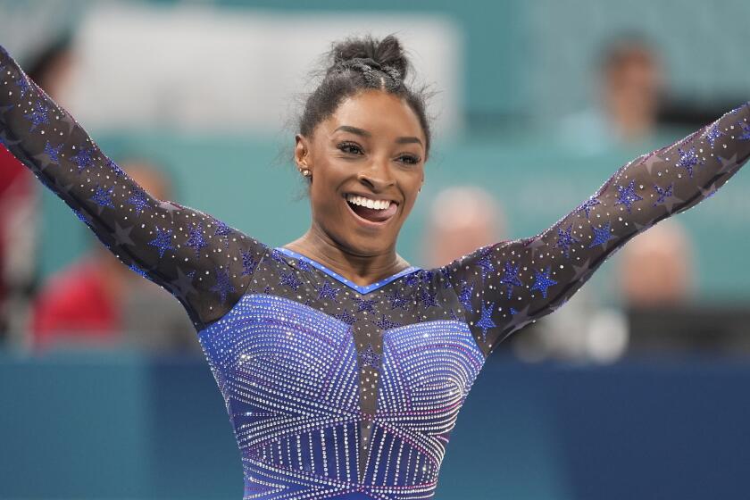 Simone Biles grins after performing on the balance beam during the women's all-around individual finals 