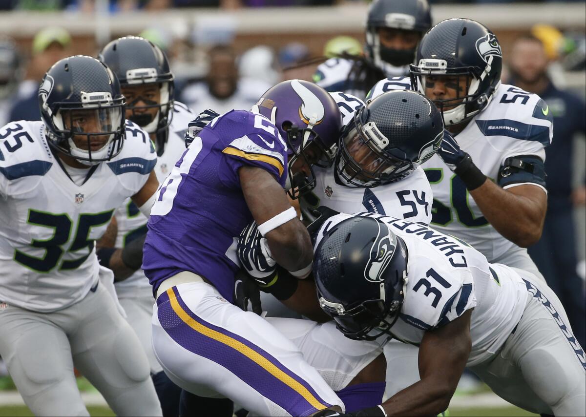 Minnesota's Adrian Peterson is stopped by Seattle defenders Bobby Wagner (54) and Kam Chancellor (31) during a Dec. 6 game in Minneapolis.