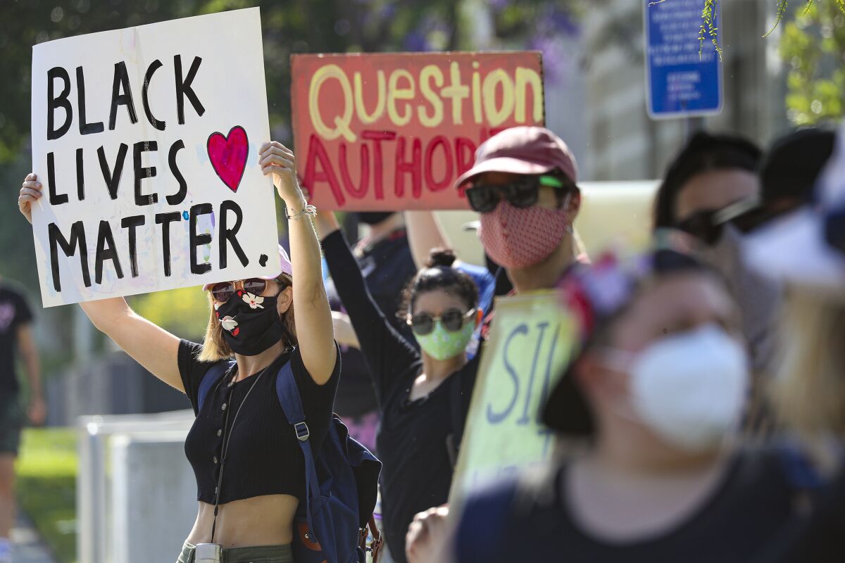 Stevie Nelson, left, joins a protest outside the North Hollywood police station.