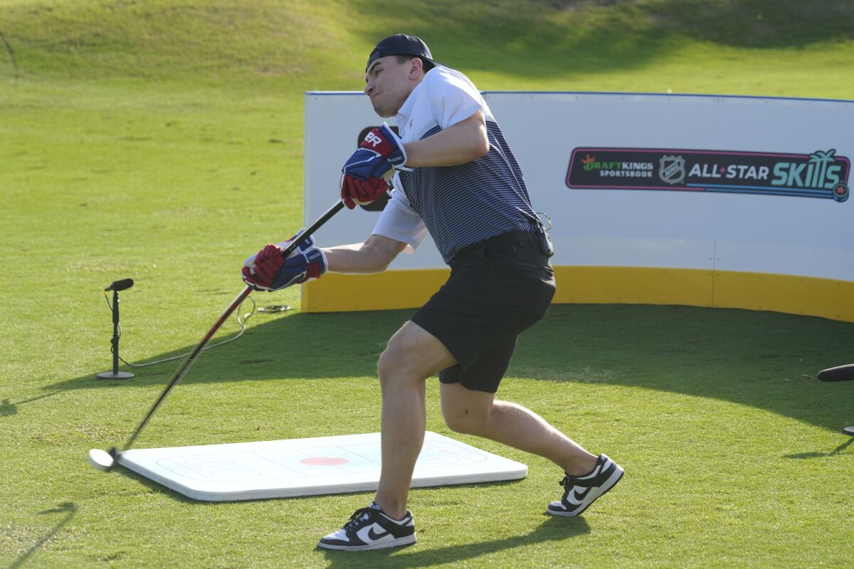 Nick Suzuki of the Montreal Canadiens, hits his first shot with a hockey stick during a golf skills competition, Wednesday, Feb. 1, 2023, in Plantation, Fla. The event was part of the NHL All Star weekend. (AP Photo/Marta Lavandier)