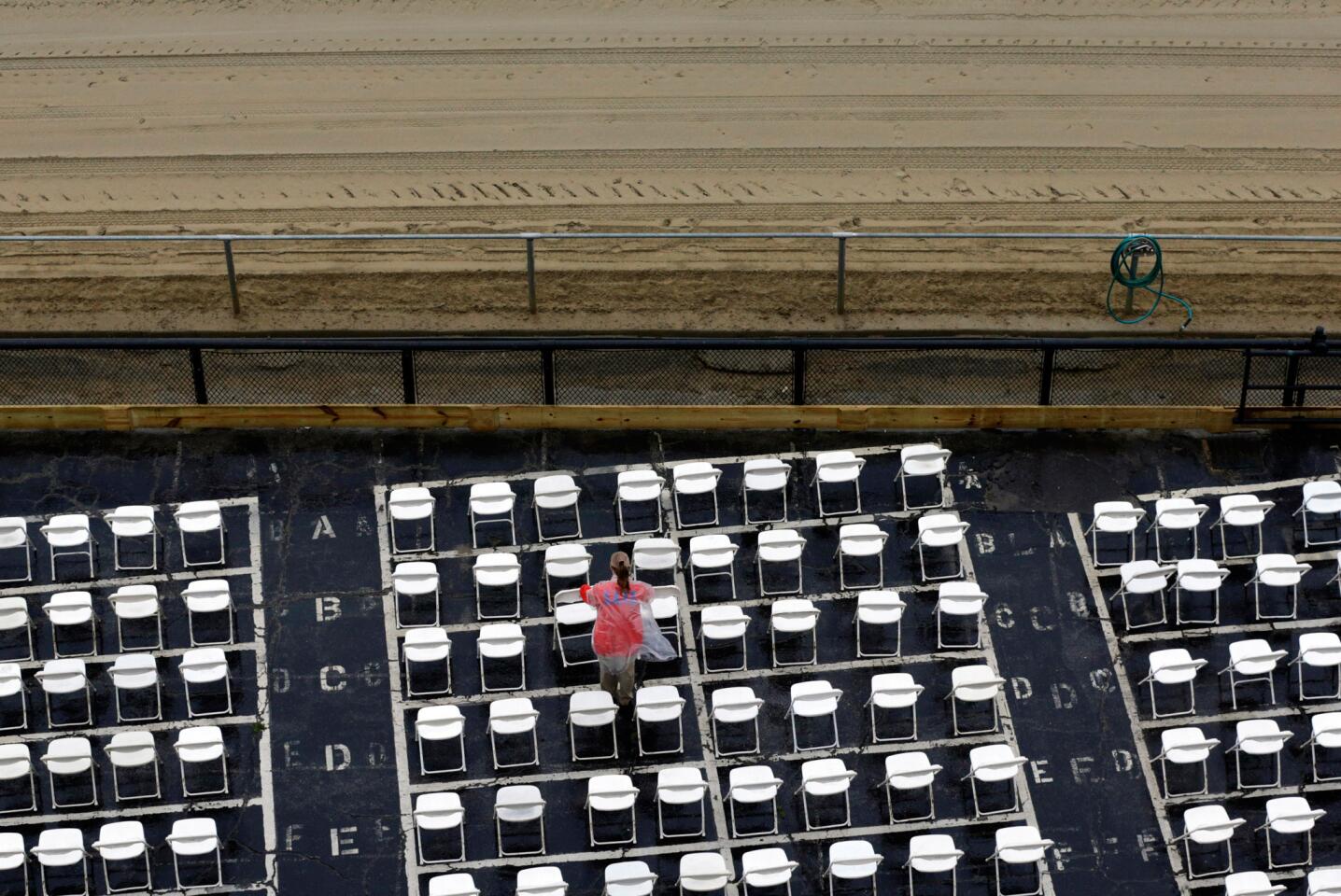 An usher clears water from trackside seats as rain falls before the 141st running of the Preakness Stakes at Pimlico Race Course.