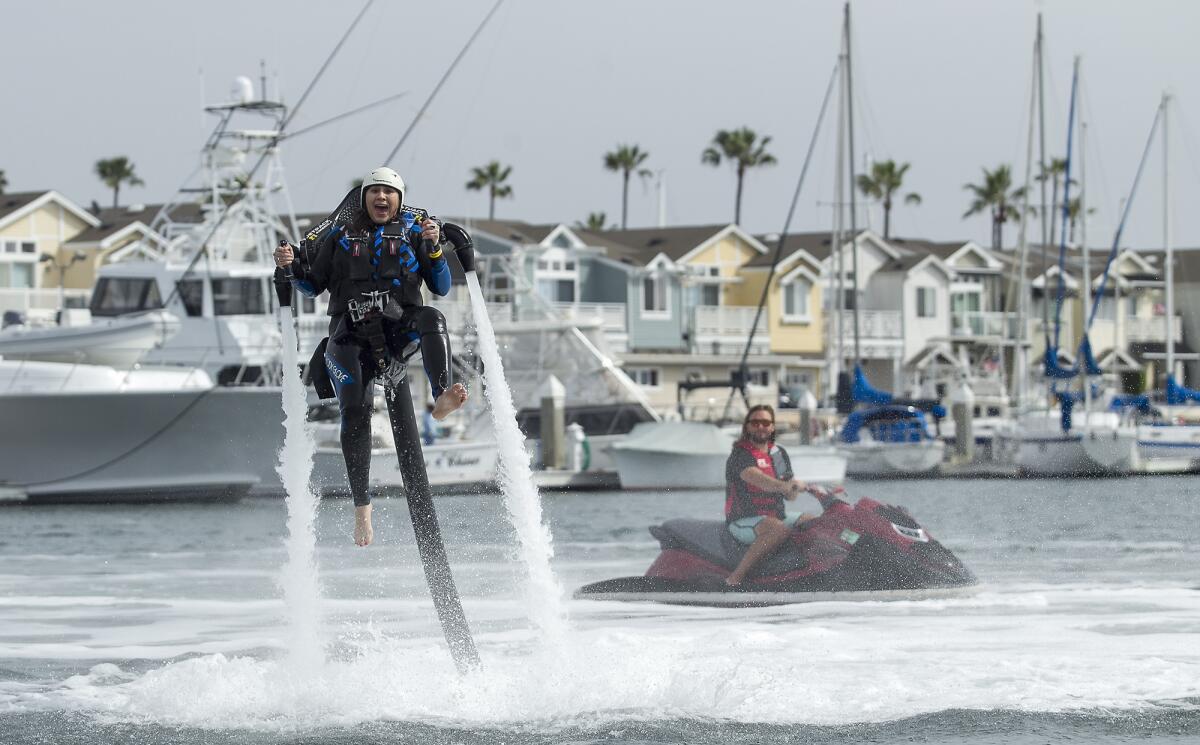 Eli Delgado takes off on a water-propelled jetpack at Newport Harbor under the watchful eye of instructor Trevor Heard of Jetpack America in February 2015. Jetpack America, Newport Beach’s only water jetpack operator, says it will leave the city next month.